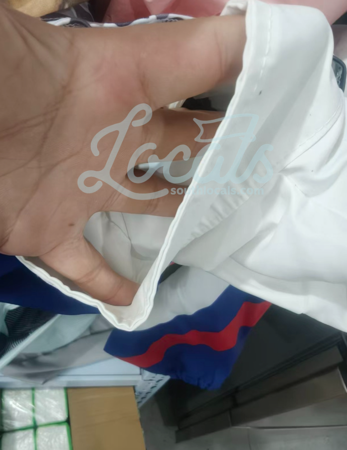 Close-up of a white cap with 'Locs' logo held by a hand.